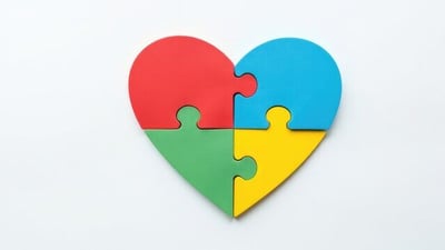 A heart made of four different coloured jigsaw pieces slotted together.